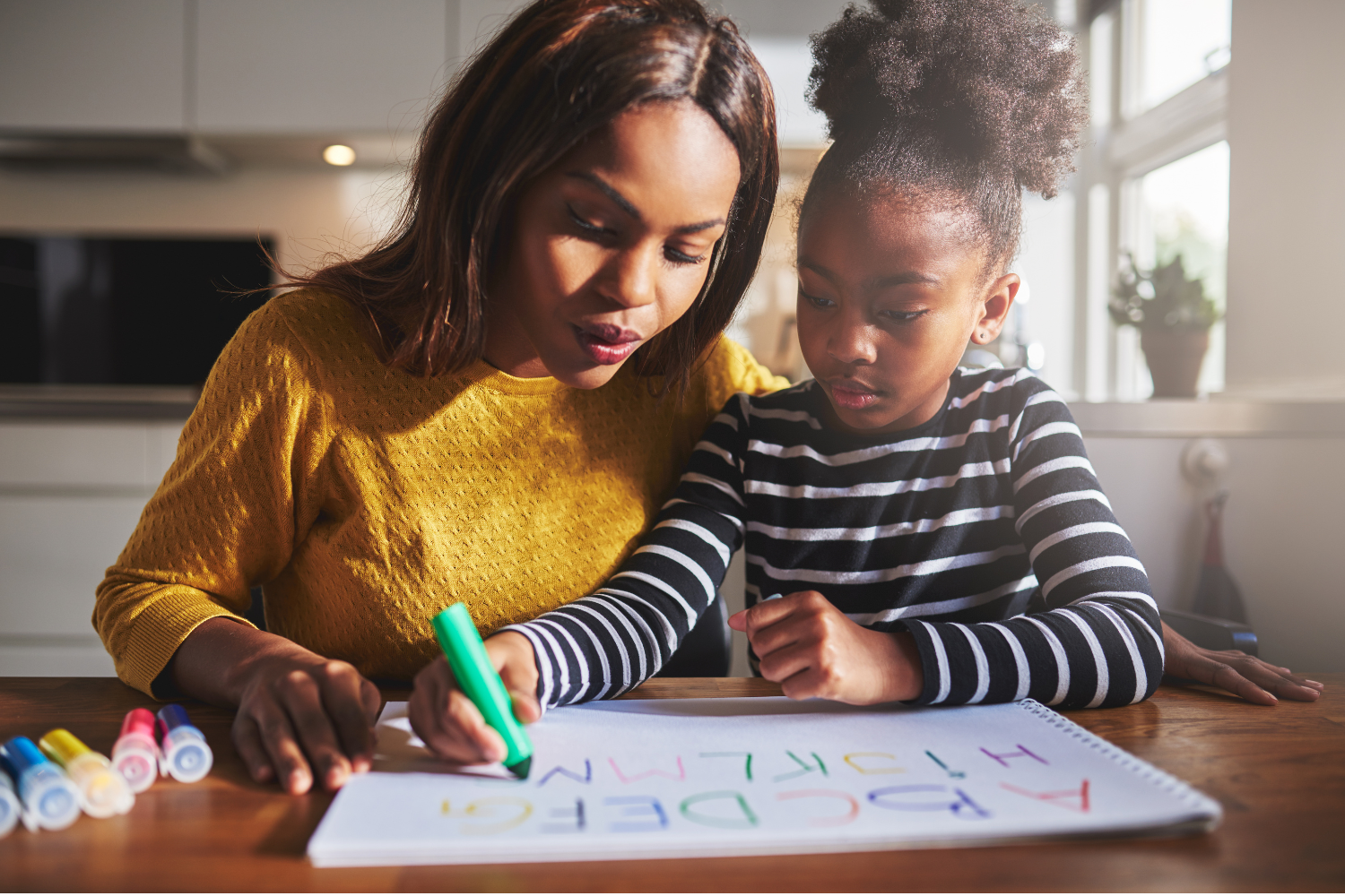 Mother teaching her young daughter to write