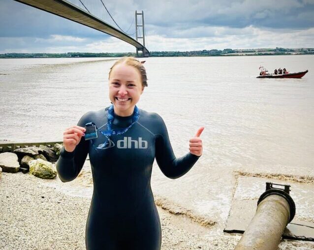 Female in wetsuit alongside the river Humber after completing the Humber swim